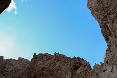 Low angle view of rock formations against clear blue sky