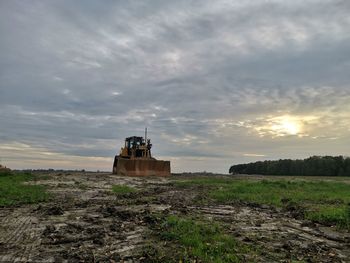 Abandoned building on field against sky during sunset