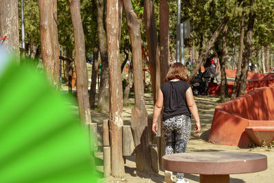 Rear view of women standing amidst trees in forest