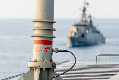 Close-up of information sign against sea against sky