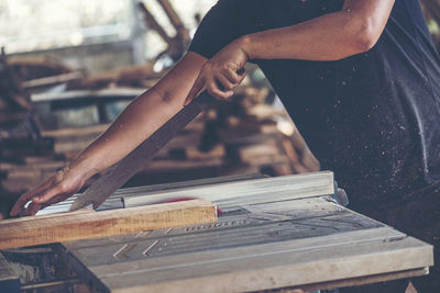 Midsection of man shaving wood at workshop