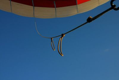 Low angle view of hanging lights against clear blue sky