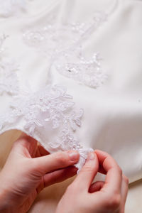 Close-up of hand sewing lace on wedding dress