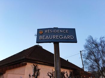 Low angle view of sign board against blue sky