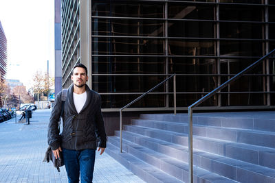 Young bearded man walking on the street next to office building