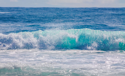 Waves splashing on sea against sky