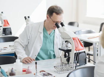 Senior researcher working with microscope in lab