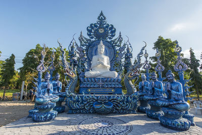 Statue against temple and building against sky