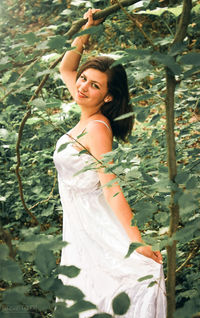 Portrait of smiling young woman standing by trees in a fairytale-like setting