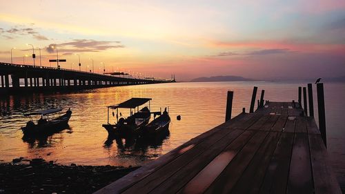 Pier over sea against sky during sunset