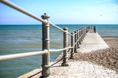 Close-up of railing by sea against sky