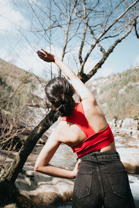 Rear view of woman standing against trees