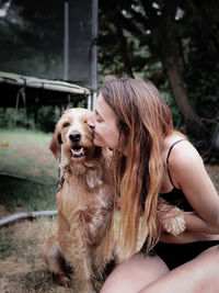 Woman in bikini with dog sitting on grass