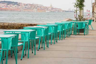 Chairs and tables at beach against sky in city