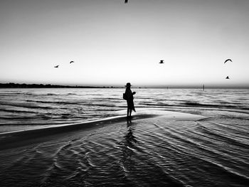 Silhouette man standing on beach against sky