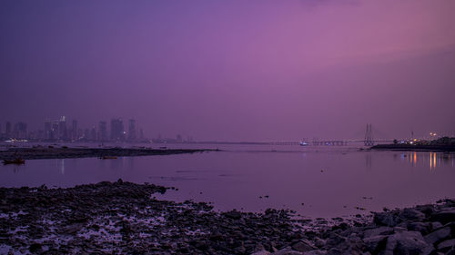 Scenic view of sea and buildings against sky during sunset