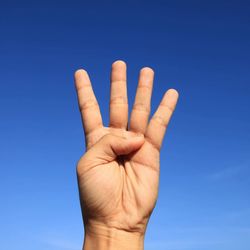 Close-up of hand against blue sky