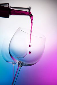 Low angle view of glass decoration hanging from pink over white background