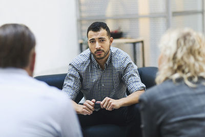 Portrait of confident businessman sitting with colleagues at office lobby