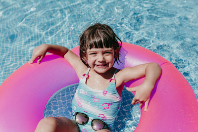 Portrait of smiling girl with inflatable ring in swimming pool