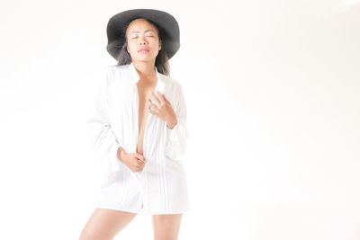Portrait of young woman standing against white background