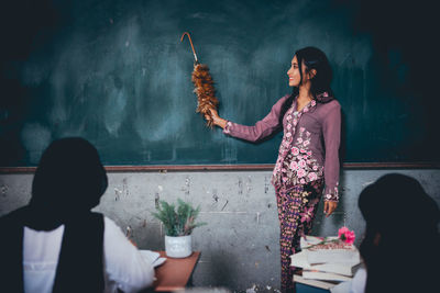 Teacher teaching over blackboard in classroom