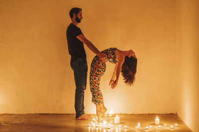 Side view of young couple standing against orange wall