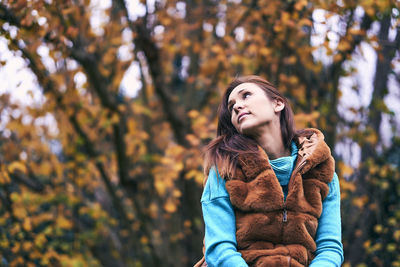 Full length of young woman holding autumn leaves