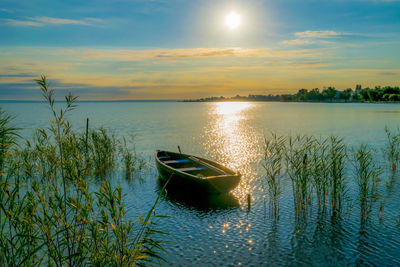 Boat moored on sea against sky during sunset