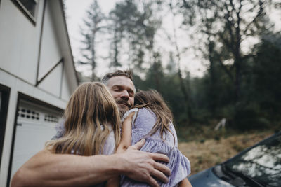 Father embracing daughters while standing in forest