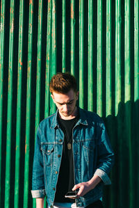 Young man looking at camera while standing against wall