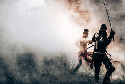 Men with arms raised on during foggy weather