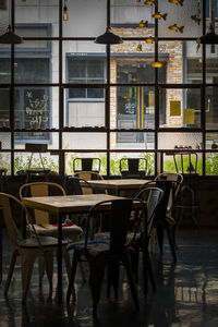 Empty chairs and tables in cafe against buildings in city