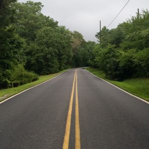 Empty road with trees in background