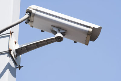 Low angle view of security cameras against sky