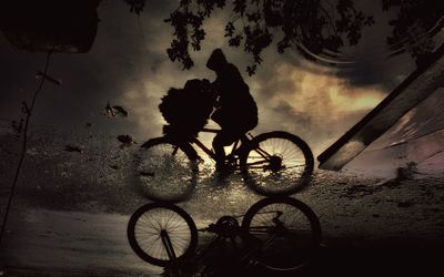 Silhouette man with bicycle on beach against sky at night