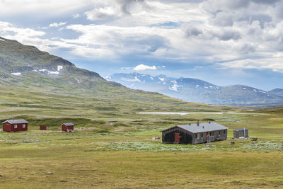 Built structure on field by mountain against sky