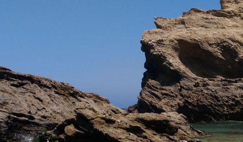 Low angle view of rock formation against clear blue sky