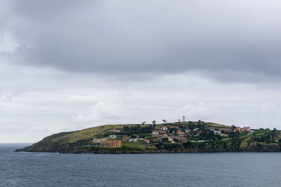 Buildings by sea against sky