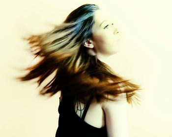 Side view of woman tossing hair against white background