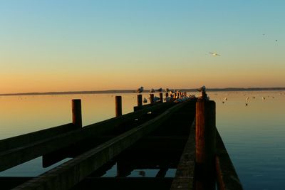 View of pier on sea at sunset