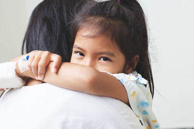 Mother carrying sick daughter against wall in hospital