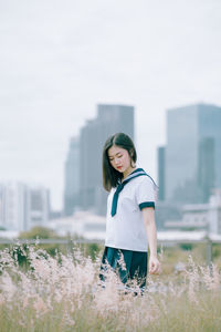 Young woman standing amidst plants on field