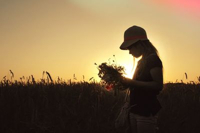 Silhouette of woman on field at sunset