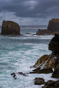 Rock formation on beach against sky