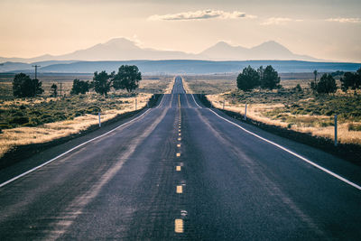 Road leading towards mountains against sky