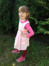 Portrait of girl with hand on hip standing on field at park