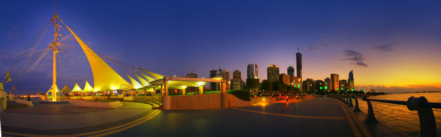 Panoramic view of illuminated city against sky at sunset