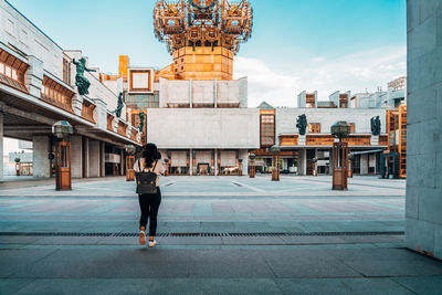 Full length rear view of woman walking against buildings in city