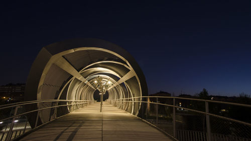 Illuminated bridge against clear sky at night